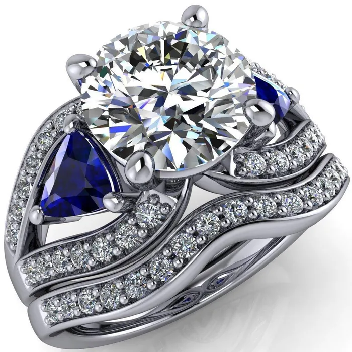 Kassandra Round Center Stone 4 Prong Trillion Blue Sapphire Side Split Shank Accent Engagement Ring Fire Brilliance Rings Kassandra Round Center Stone 4 Prong Trillion Blue Sapphire Side Split Shank Accent Engagement Ring Fire Brilliance Rings